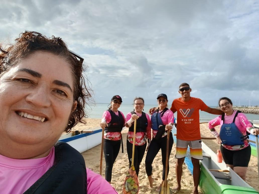 Selfie mostra Rilka Barbosa, em primeiro plano, com amiga Ana Paula Freire ao fundo, ao lado de outras sobreviventes do câncer de mama e professor de canoagem na orla de Fortaleza.
