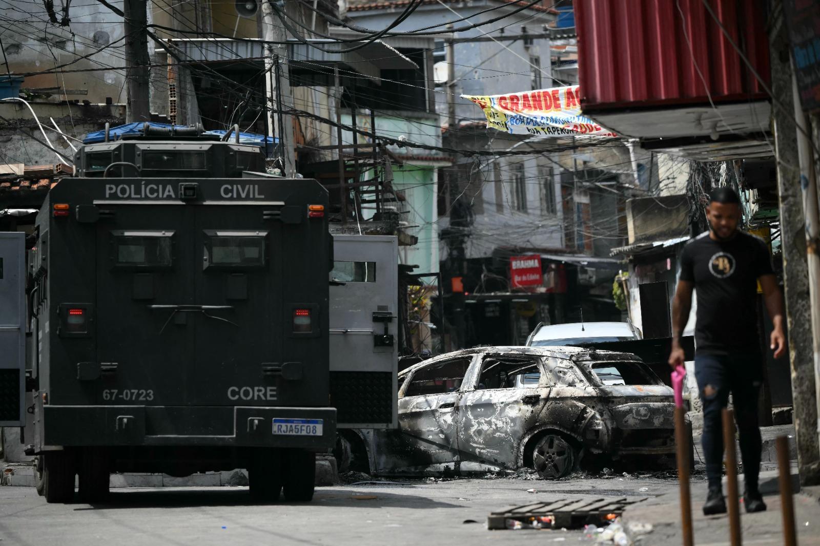 Tanque adentra uma comunidade no Rio de Janeiro, e encontra carros queimados formando uma barricada.