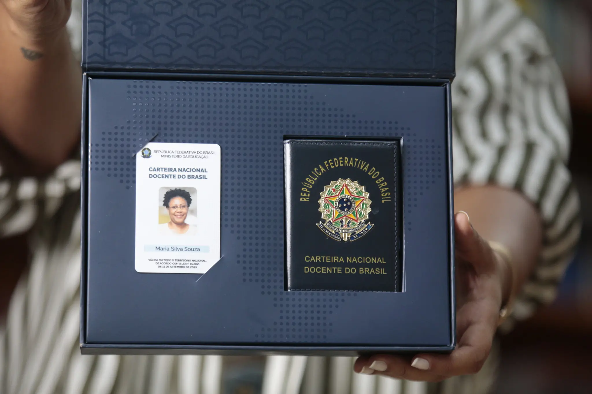 Professora mostra caixa com a carteira nacional docente do Brasil.
