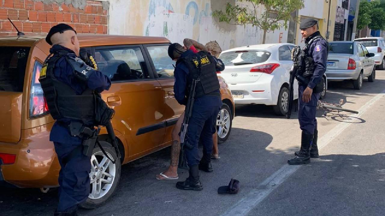 Na imagem os policias estão revistando o suspeito.