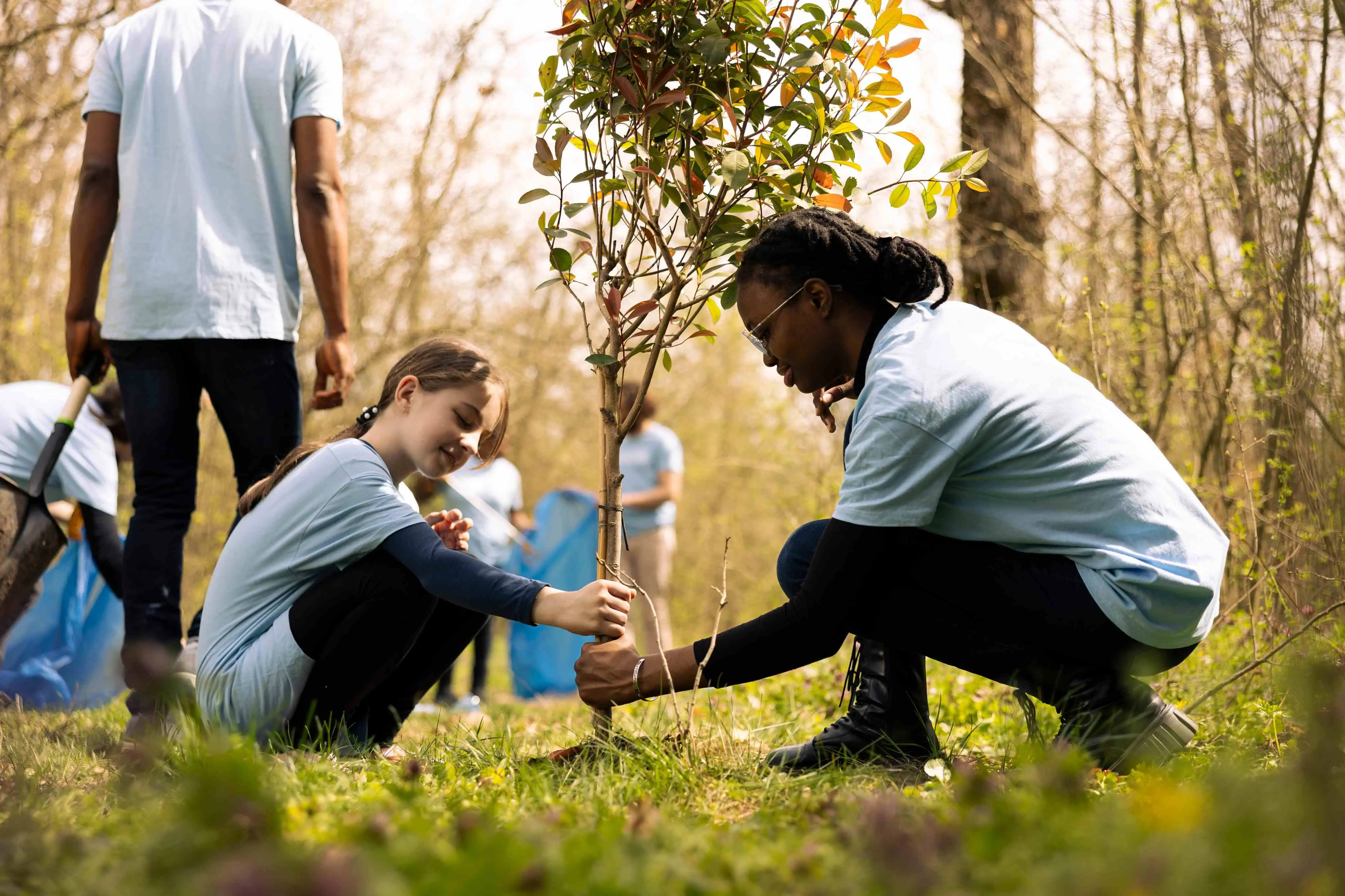Imagem de uma criança plantando uma árvore com uma mulher para uma matéria sobre saiba o que são as COPs do clima.