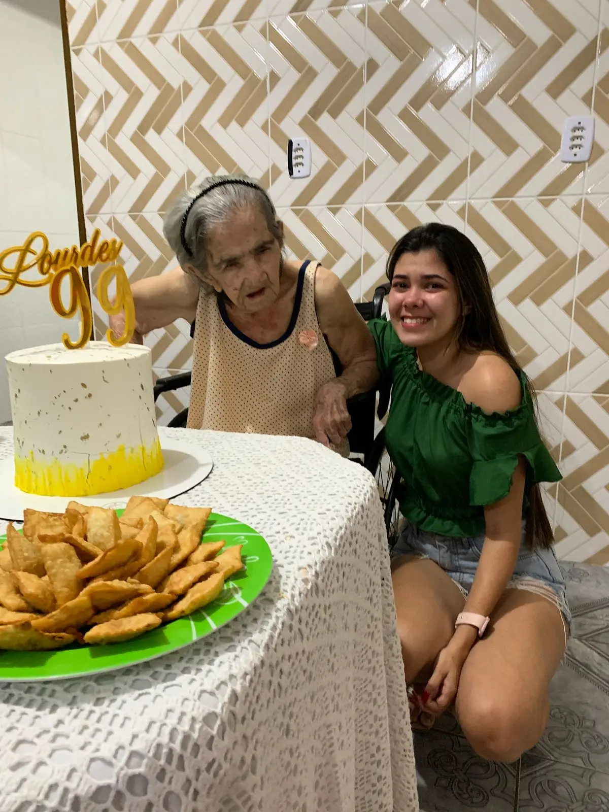 Celebrando aniversário com avó e neta, com bolo de aniversário decorado com '99', na festa com gelo, família feliz, ambiente acolhedor, fotos de aniversário.