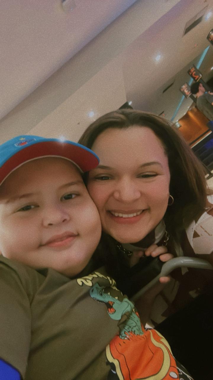 Família feliz no shopping, com mãe e filho sorrindo para a câmera, criando momentos especiais juntos.