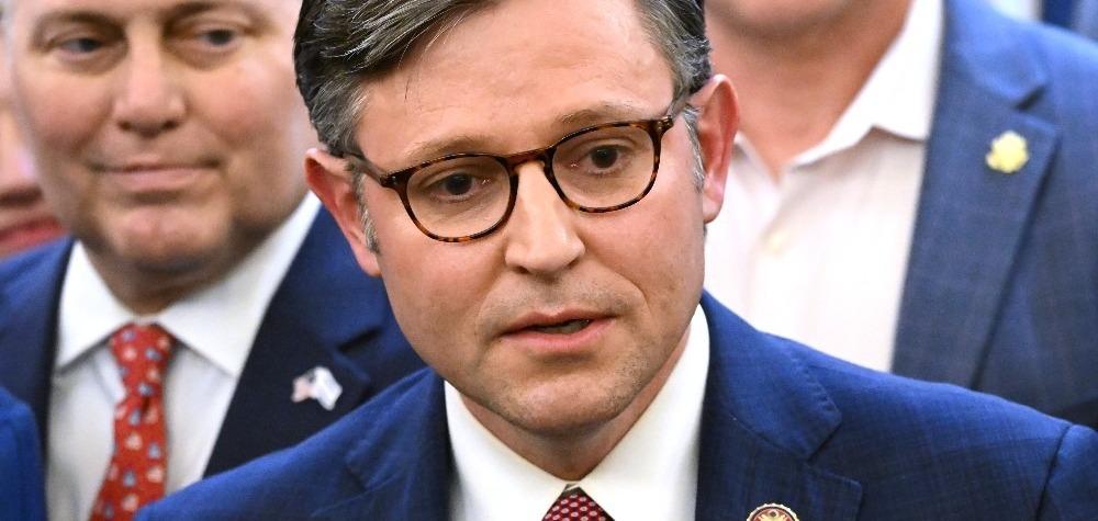 Presidente da Câmara, Mike Johnson, de terno azul, fala em coletiva.