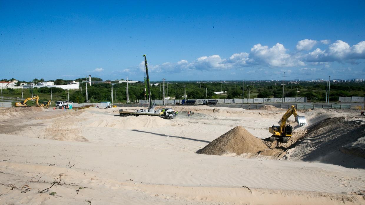 Terreno amplo com montes de areia e caminhão de construção.
