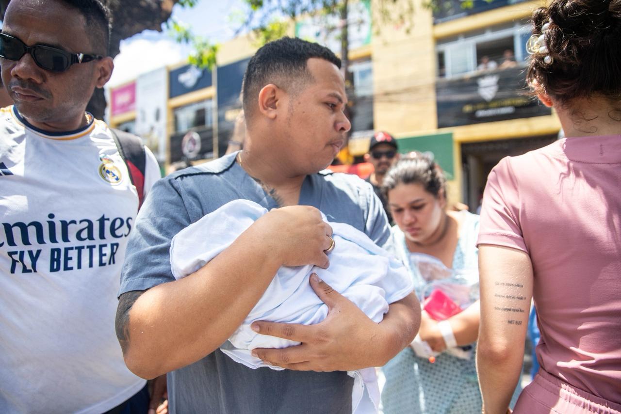 Imagem mostra homem com recém-nascido nos braços o transportando para um local segura após incêndio no hospital césar cals em Fortaleza.