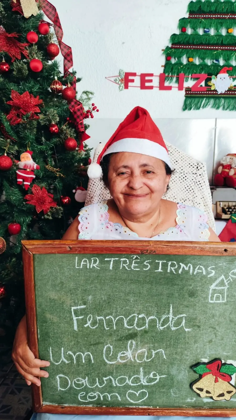 Na imagem, uma idosa está segurando uma lousa com o pedido de natal, na lousa está escrito o que a idosa pediu.