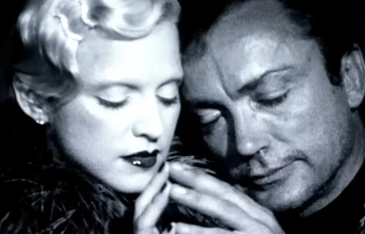 Udo e Madonna no clipe de deeper and deeper, tocando a ponta dos dedos um do outro.