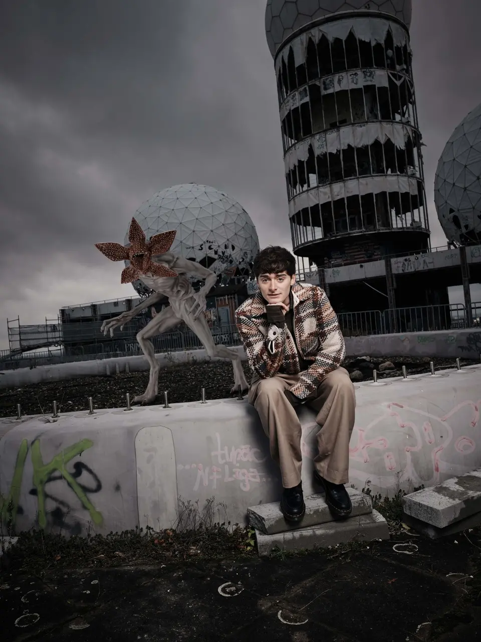 Noah Schnapp sentado vestindo uma camisa quadriculada em foto de ativação da Netflix.