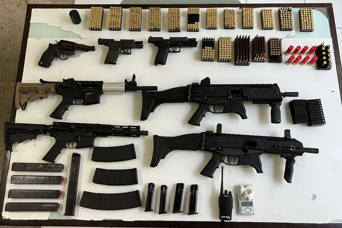 A foto mostra várias armas de fogo e munições, apreendidas pela Polícia, em cima de uma mesa branca.