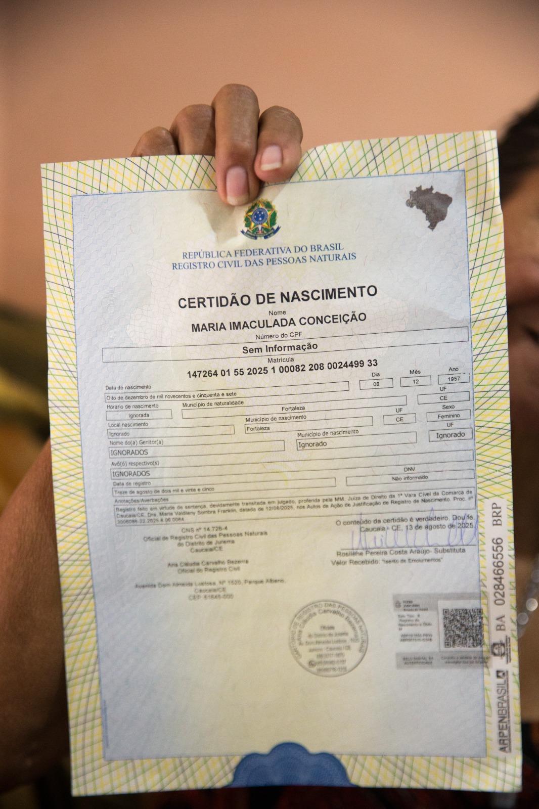 Na imagem, close-up de uma mão segurando uma Certidão de Nascimento (Certidão de Nascimento) brasileira oficial. O documento está em papel de segurança e exibe o brasão da República Federativa do Brasil no topo. O nome do indivíduo é 