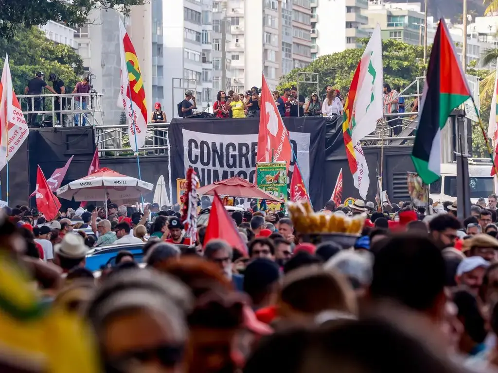 Imagem mostra pessoas com bandeiras e cartazes em frente a trio elétrico em protesto político no rio de janeiro.