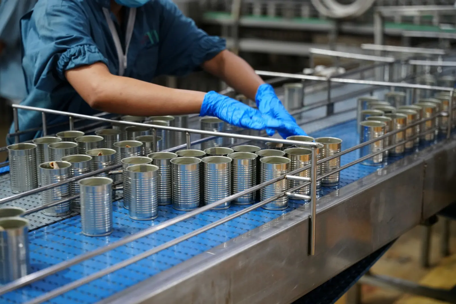 Dentro de uma fábrica, uma pessoa separa a fabricação de latas de alumínio. Imagem usada em matéria sobre direitos de quem irá trabalhar no Natal e Ano Novo