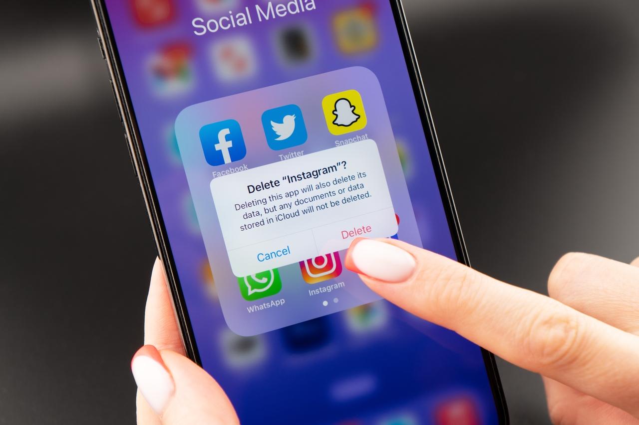 Pessoa segura celular prestes a deletar o aplicativo Instagram do aparelho.