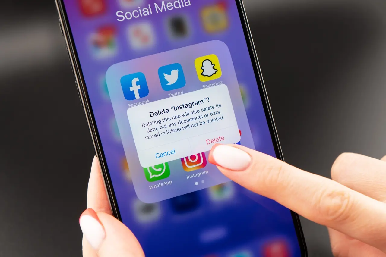 Pessoa segura celular prestes a deletar o aplicativo Instagram do aparelho.
