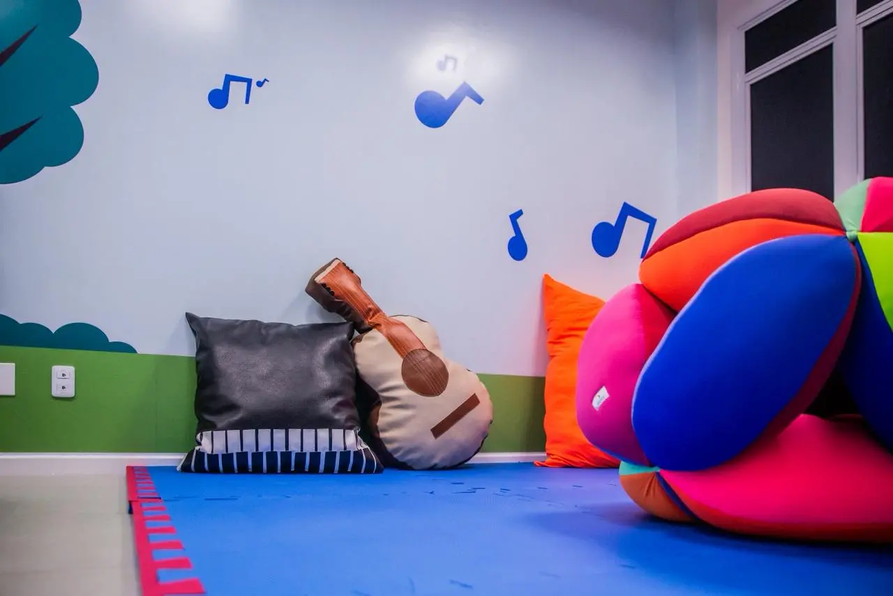 Espaço com almofadas e decoração musical para estimulação sensorial.