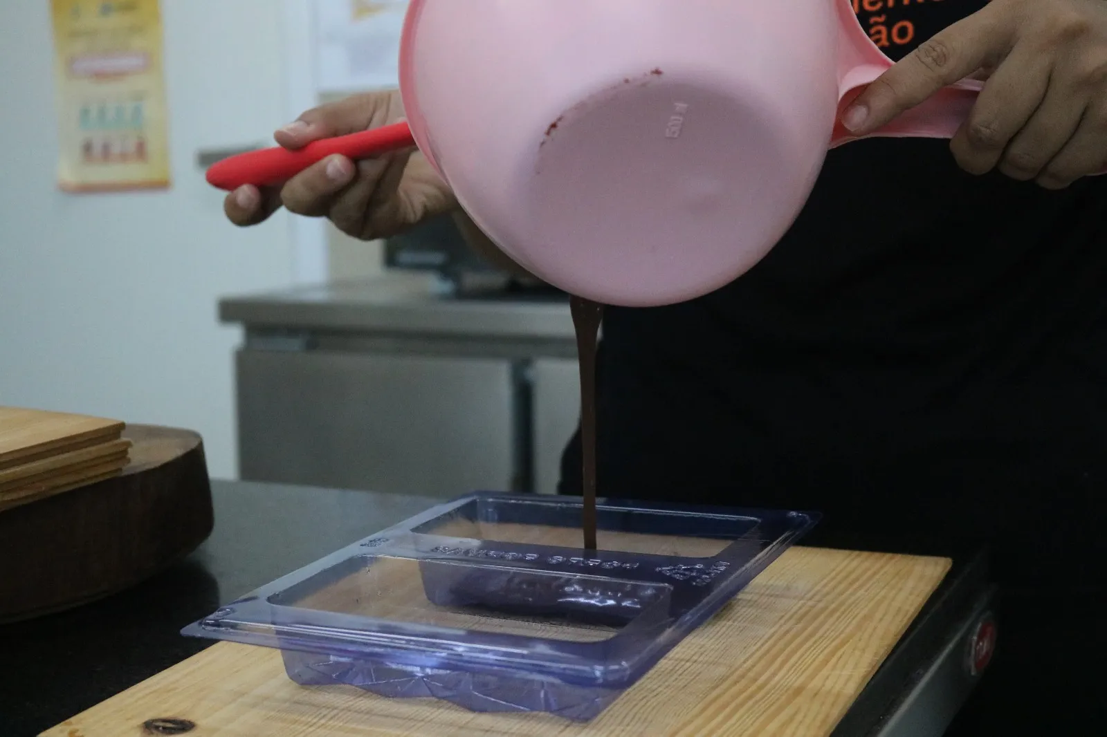 Despeje uma parte do chocolate temperado na forma, garantindo que todo o fundo e as laterais sejam cobertos.