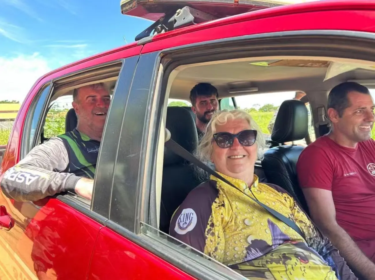Família resgatada sendo encaminhada ao pronto-socorro dentro de carro vermelho acompanhados de um integrantes da equipe do corpo de bombeiros.