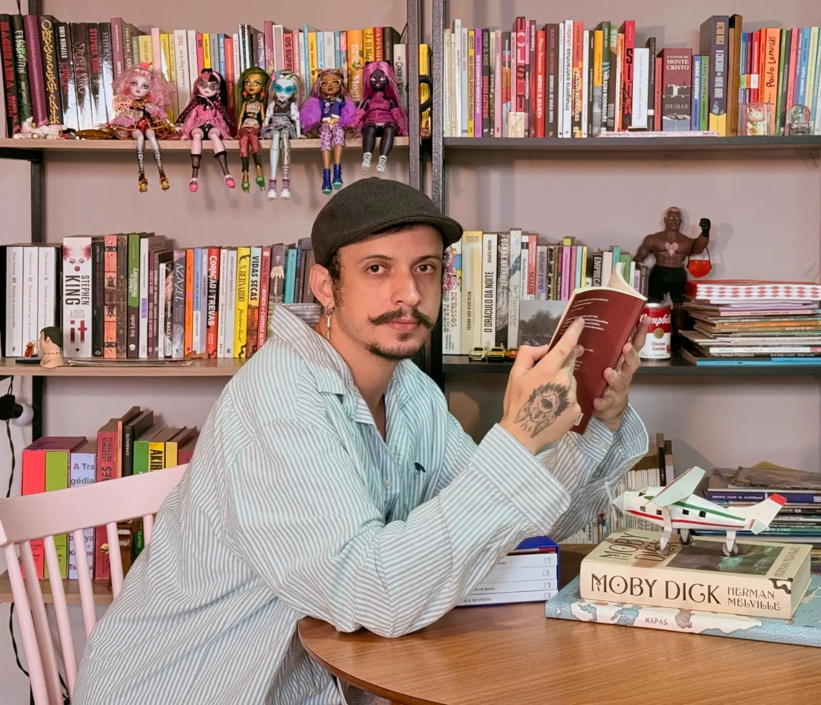 Charles Lessa segurando um livro e posando para a foto com expressão séria.