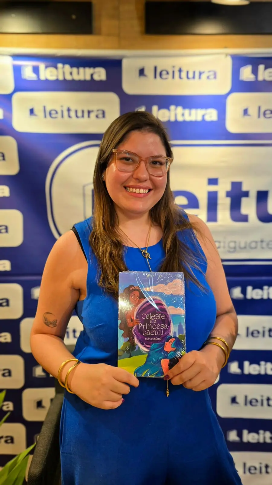 A escritora Sofia Osório segurando um livro e posando para a foto com aparência feliz.