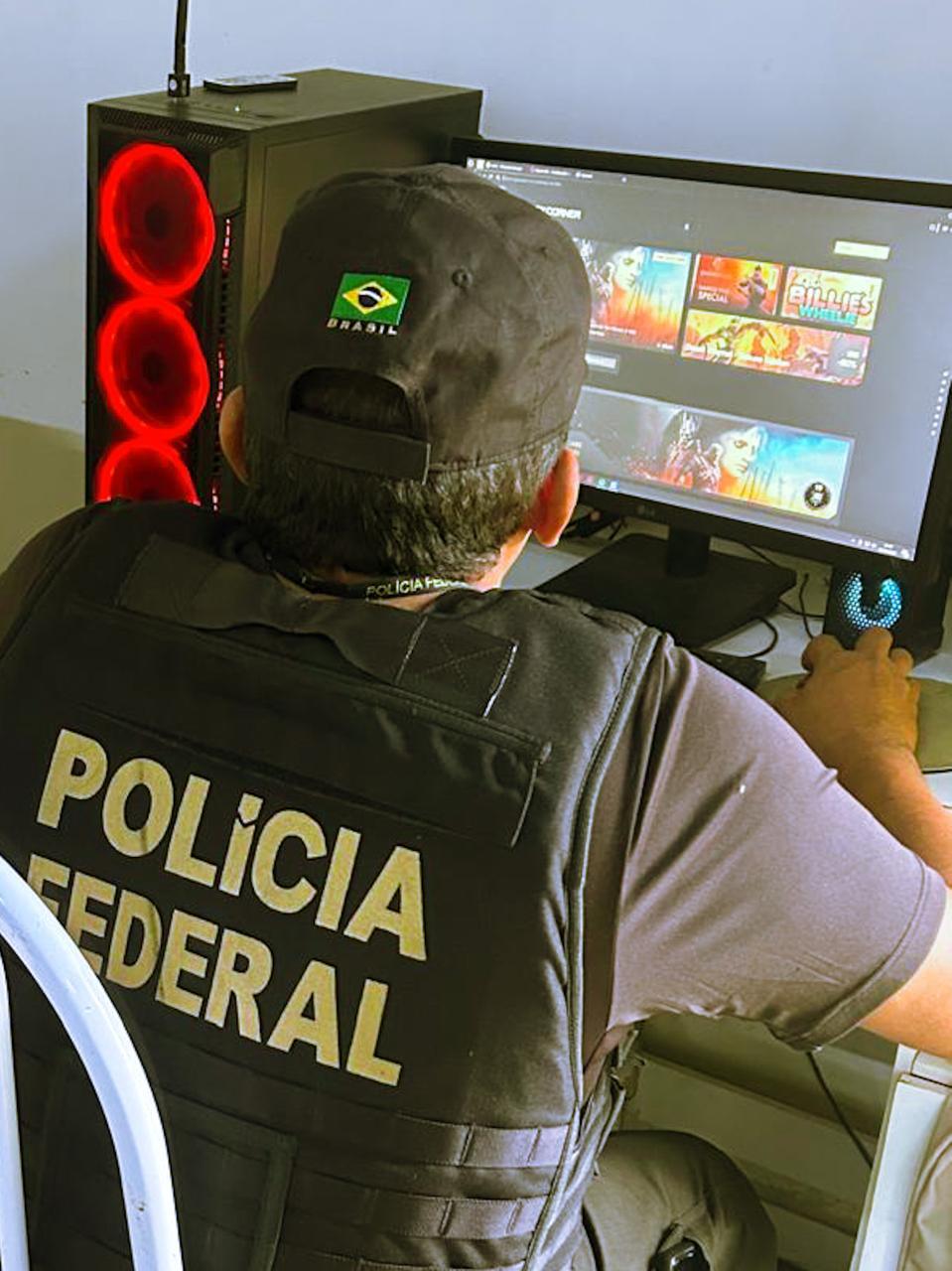 Imagem mostra policial federal durante uma operação em um computador.