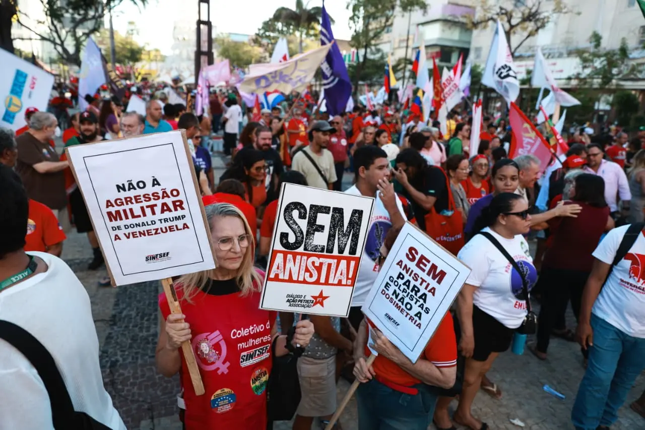 Dezenas de pessoas reunidas durante ato em defesa da democracia na Praça de Ferreira. Na imagem, uma mulher segura placas em defesa da Venezuela e contra a Anistia.