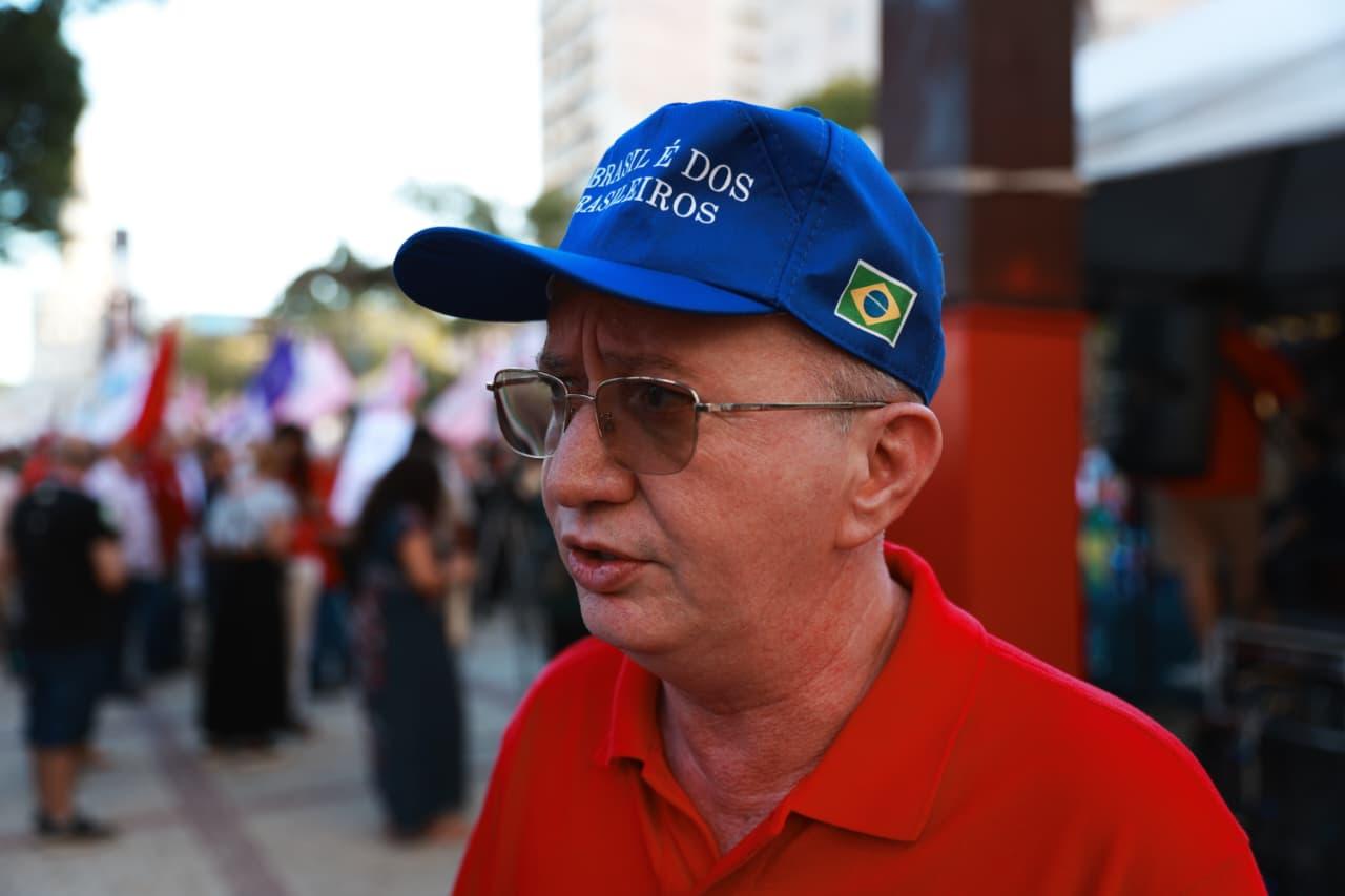 Conin, presidente do PT Ceará, durante entrevista no Ato da Praça no Ferreira. Ele veste uma camisa polo vermelha e um boné azul.