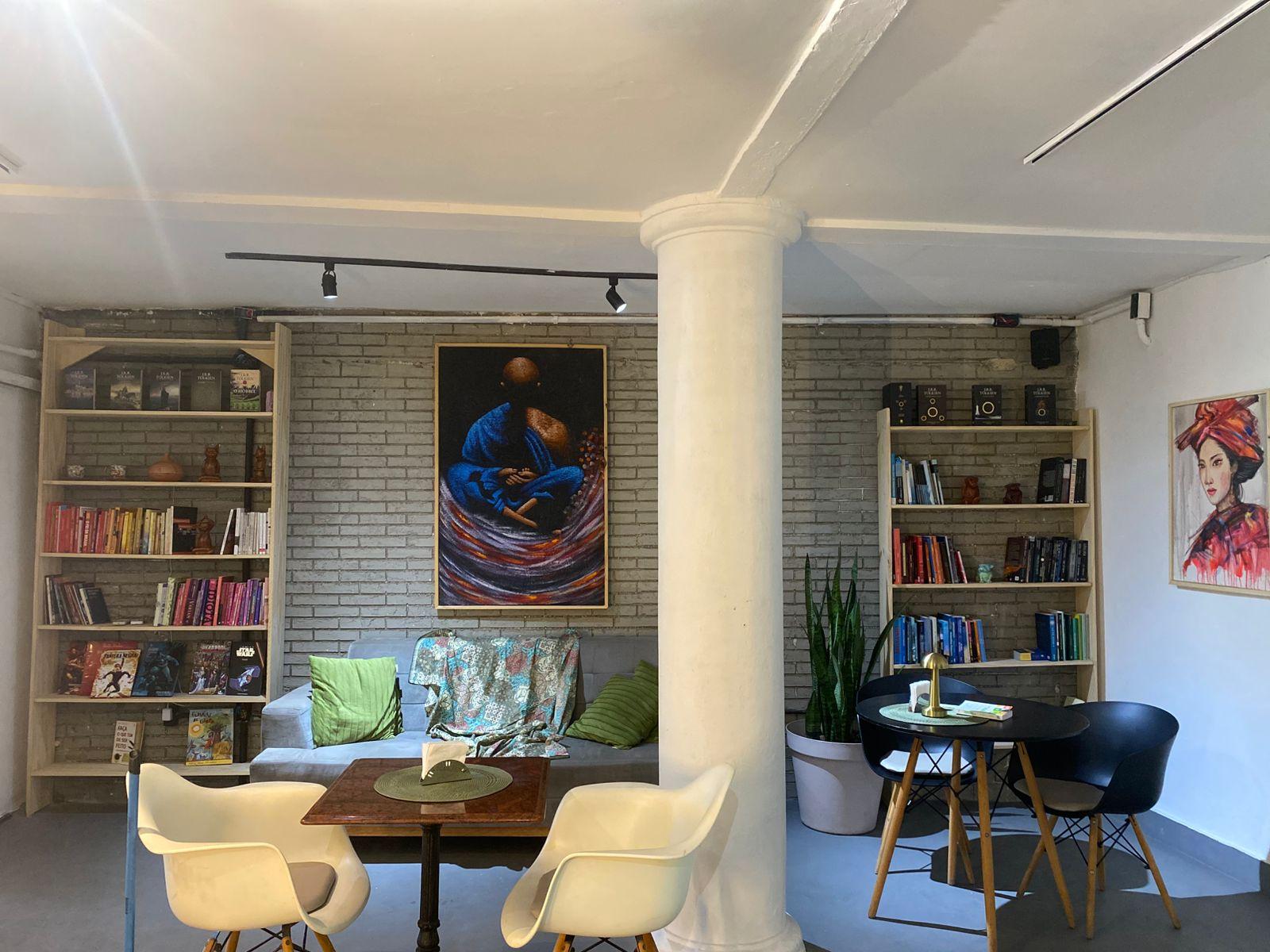 Foto interna do Café Giardini onde tem prateleiras com livros, mesas e cadeiras.