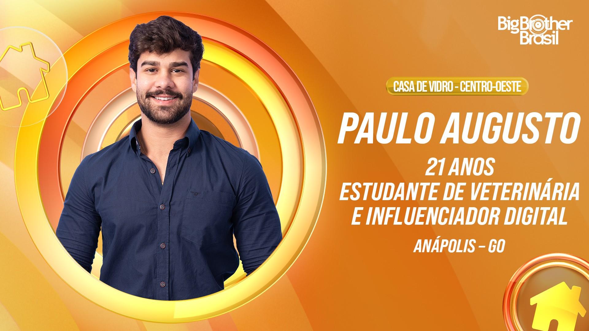 Paulo Augusto, participante da Casa de Vidro do Big Brother Brasil, sorrindo e usando camisa azul escura. Texto na imagem informa: 21 anos, estudante de veterinária e influenciador digital, de Anápolis-GO.