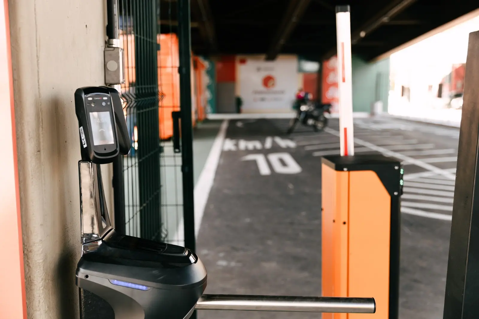 Catraca com leitor biométrico e cancela eletrônica na entrada da Paradinha, em Fortaleza. Ao fundo, vê-se a área de estacionamento e sinalização do ponto de apoio aos motociclistas.