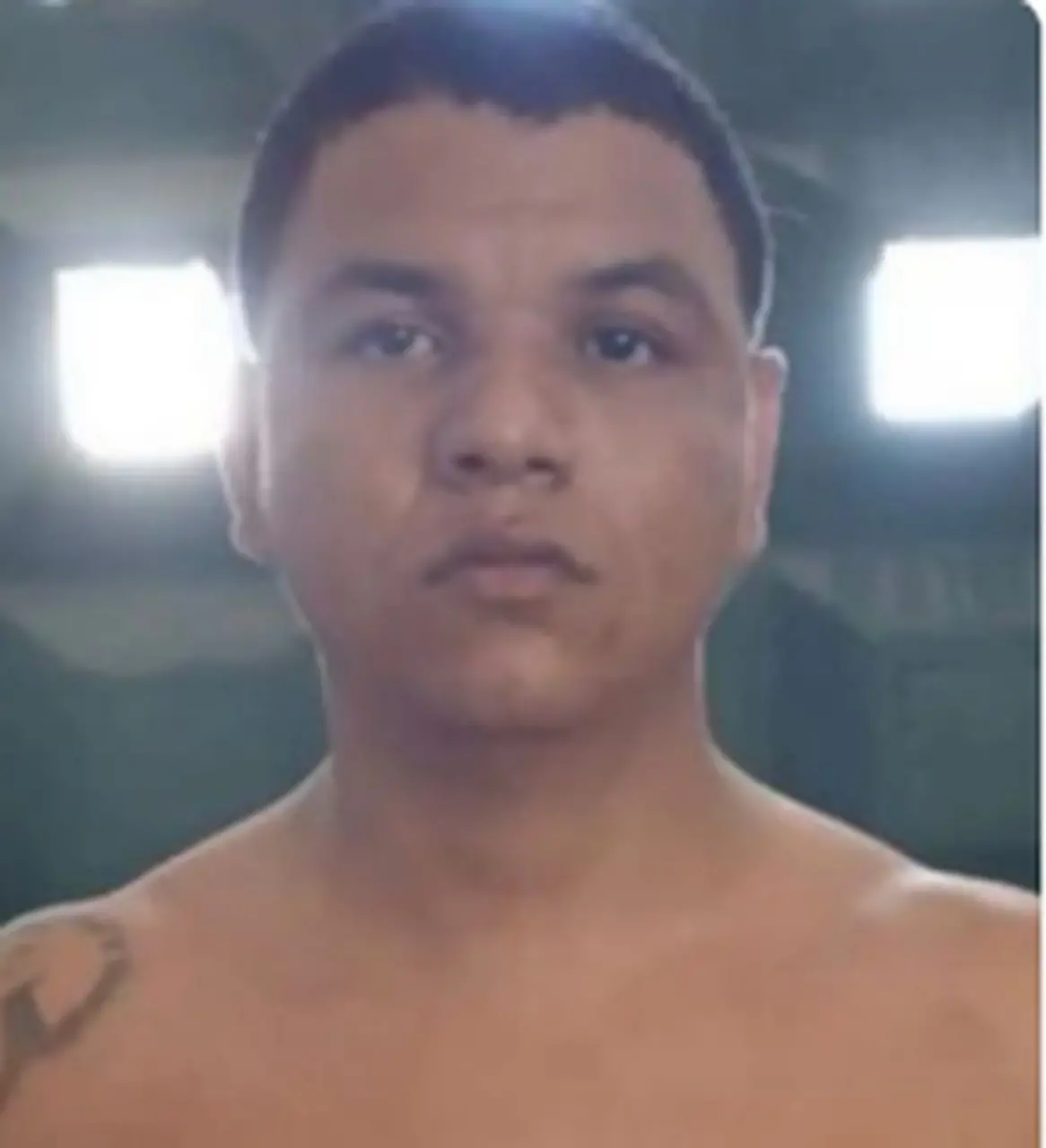 Homem jovem com pele clara, cabelo curto e expressão séria, posa de frente em ambiente interno, provavelmente em uma gravação ou foto casual.