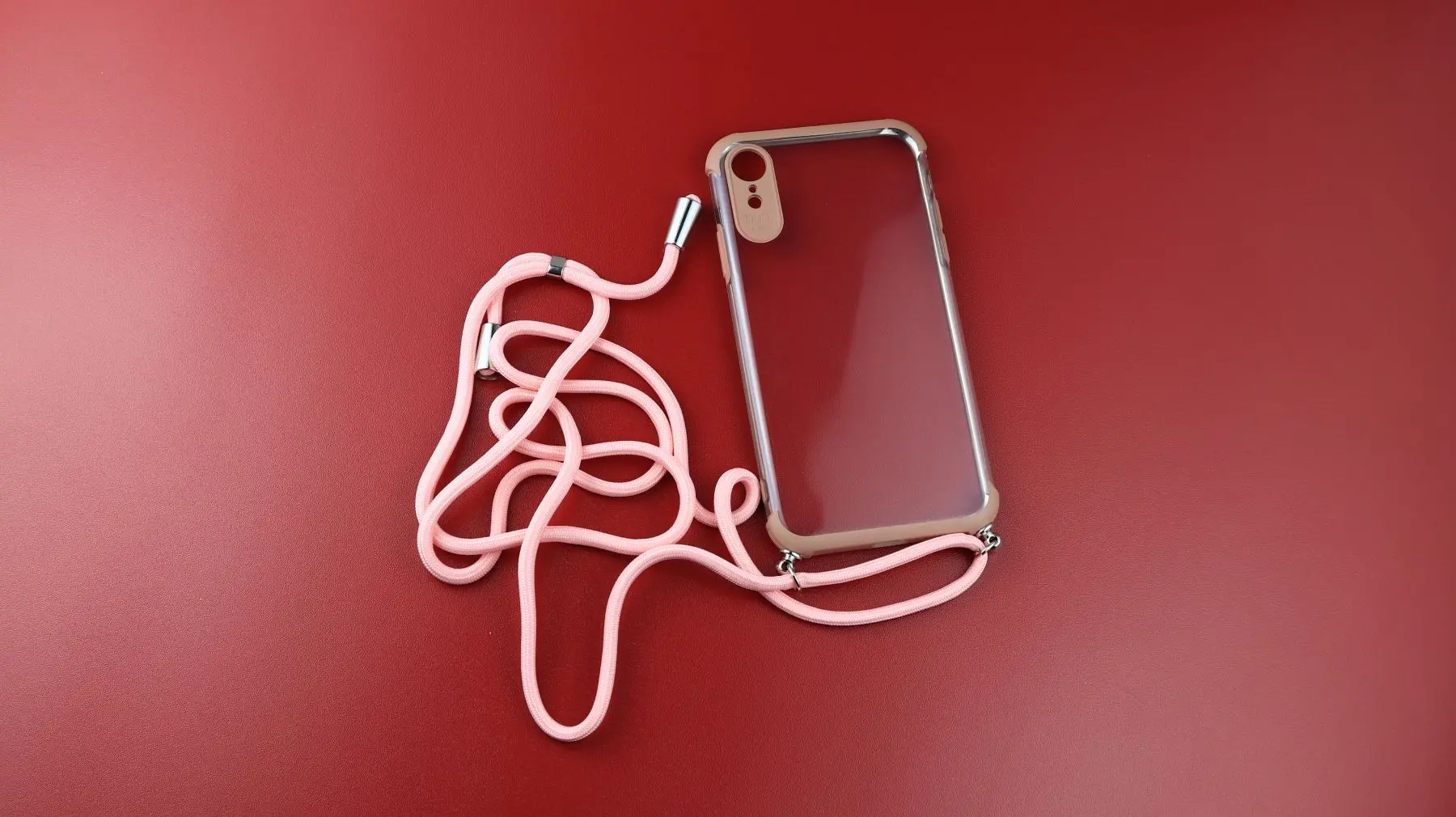 capa de celular com cordinha, sobre um fundo vermelho.