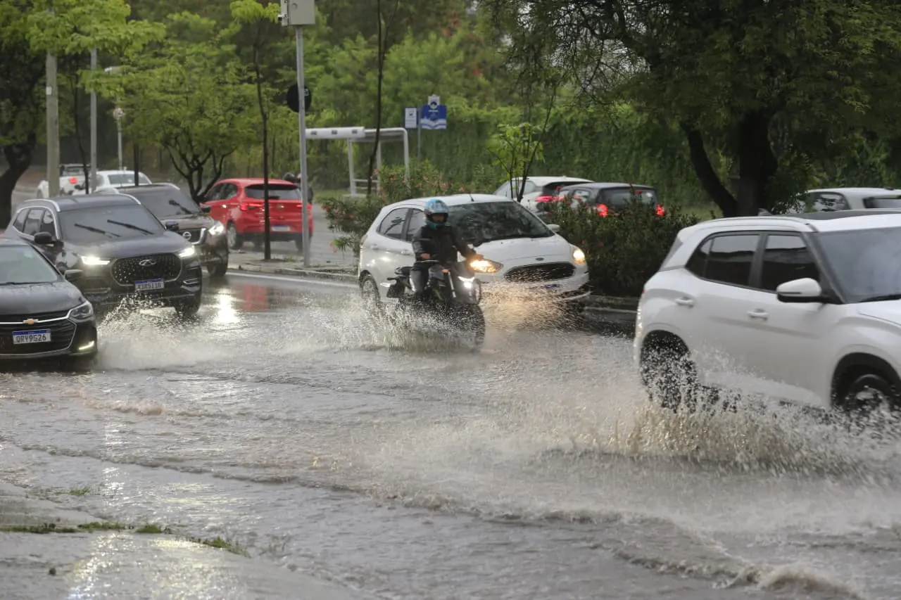 Avenida alagada com carros e motos.