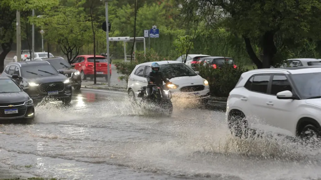 Avenida alagada com carros e motos.