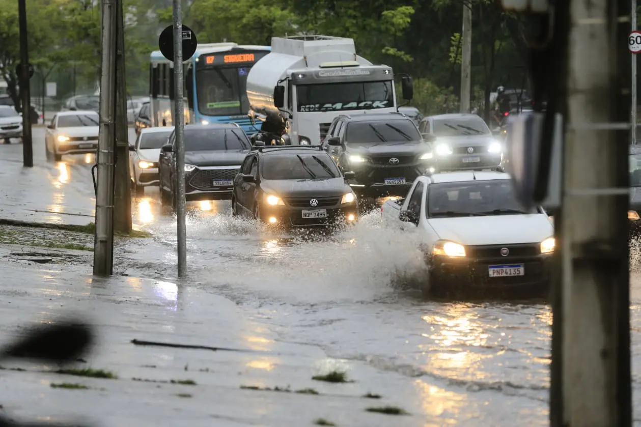 Avenida com muita água e muitos carros em dia de chuva.