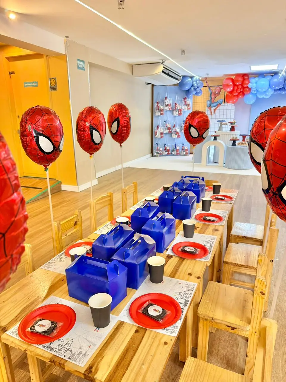 Na imagem, uma mesa de festa infantil decorada com o tema Homem-Aranha, preparada para receber os pequenos convidados. A composição é vibrante e organizada, predominando as cores vermelho e azul.