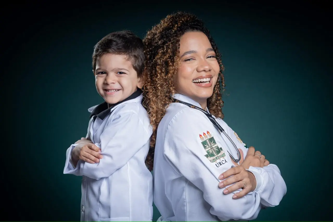 O pequeno de 3 e a mãe um de costas para o outro com um fundo atrás.