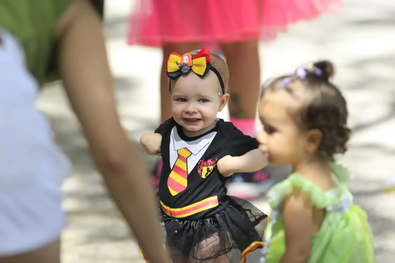 Criança pequena fantasiada com uniforme da Grifinória.