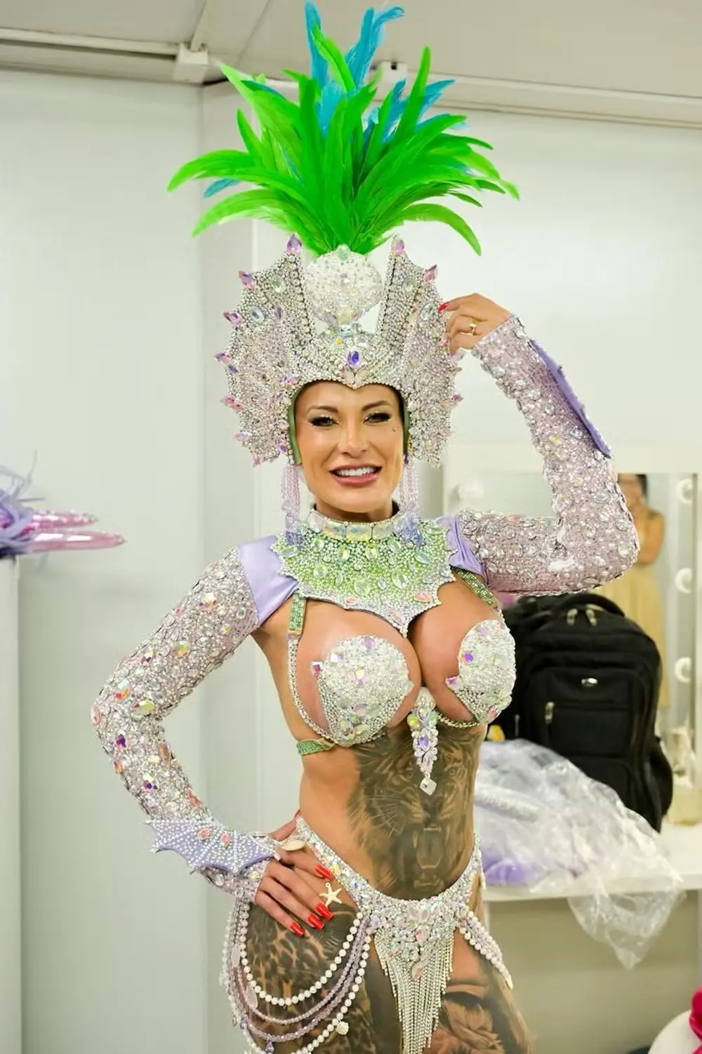 Andressa Urach usa fantasia com brilhantes prateados e pluma verde na cabeça.