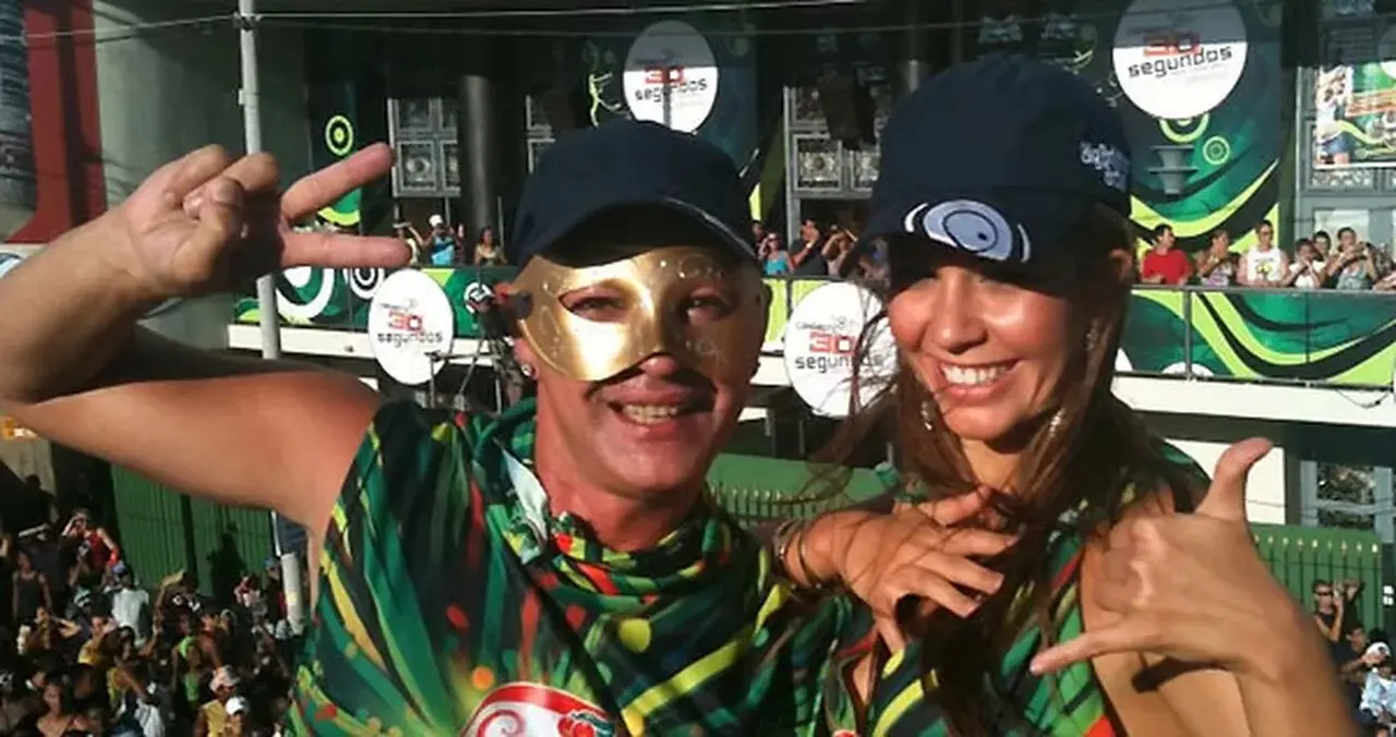 Homem e mulher com blusa verde posando para foto, ele com máscara dourada.