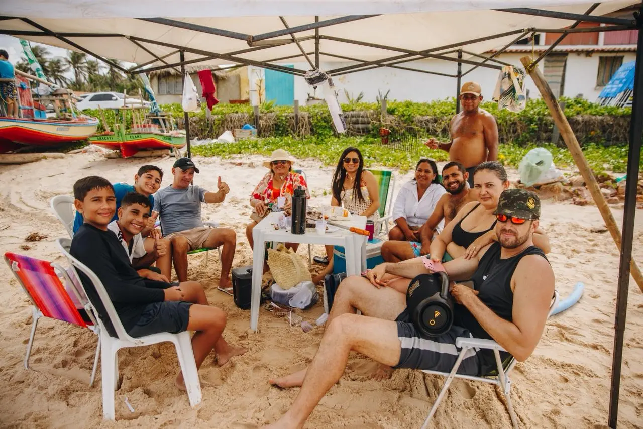 Turistas em barraca de praia na cidade de Aracati. Nas mesas, comidas e bebidas estão dispostas.
