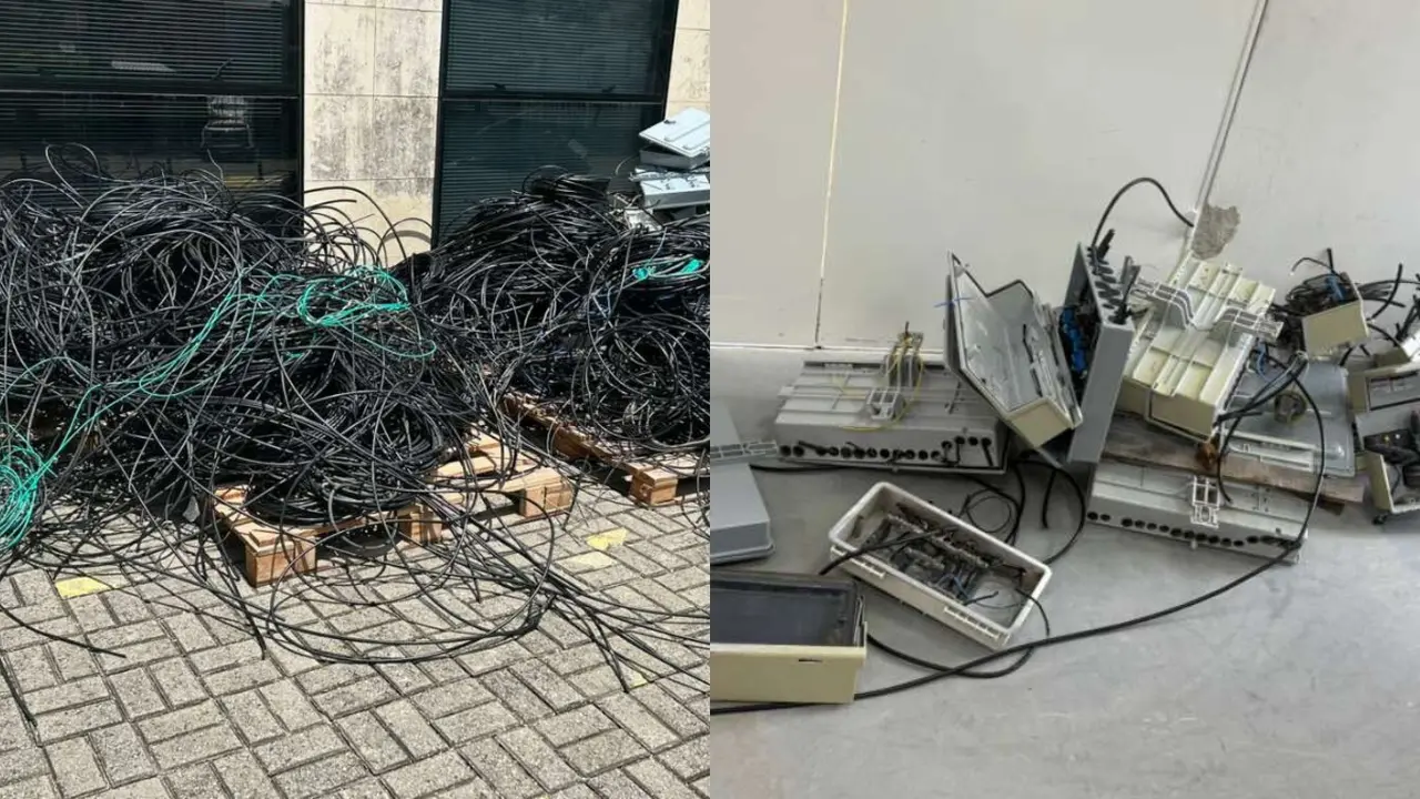 Cabos elétricos e equipamentos de telecomunicação apreendidos, empilhados em pallets e no chão após remoção de infraestrutura.