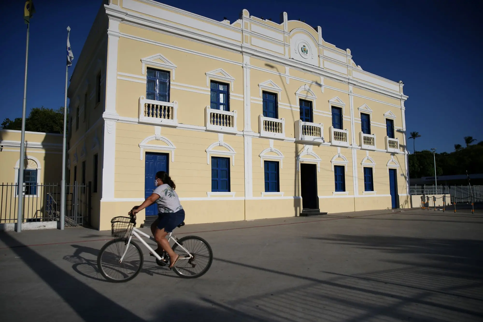 fachada do palácio do bispo, paço municipal de fortaleza. em frente ao prédio, uma pessoa passando de bicicleta.