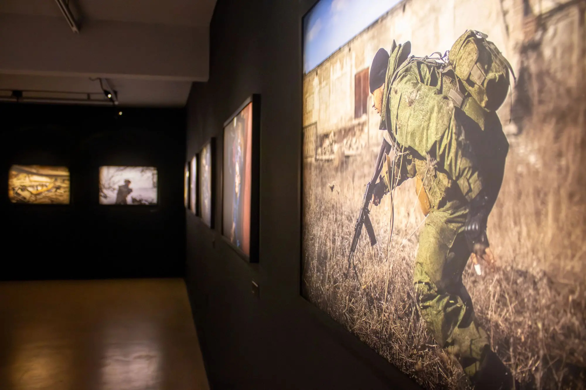 imagens da exposição no museu da fotografia fortaleza. em destaque, imagem de um homem andando com armamento.
