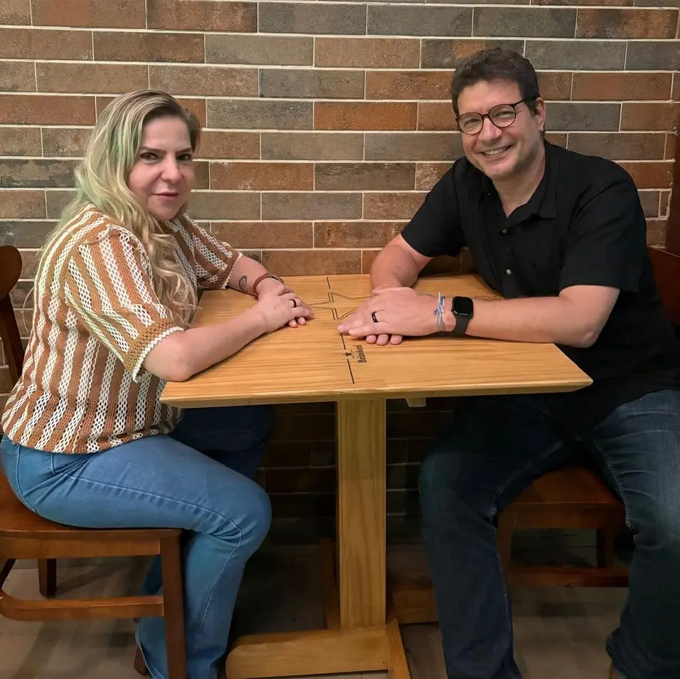 Luizianne Lins ao lado do deputado estadual Renato Roseno. Eles estão em uma mesa e sorriem para a foto.