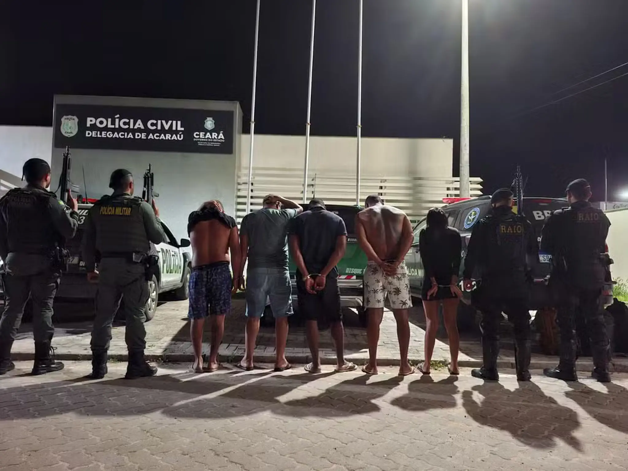 As pessoas presas aparecem de costas.