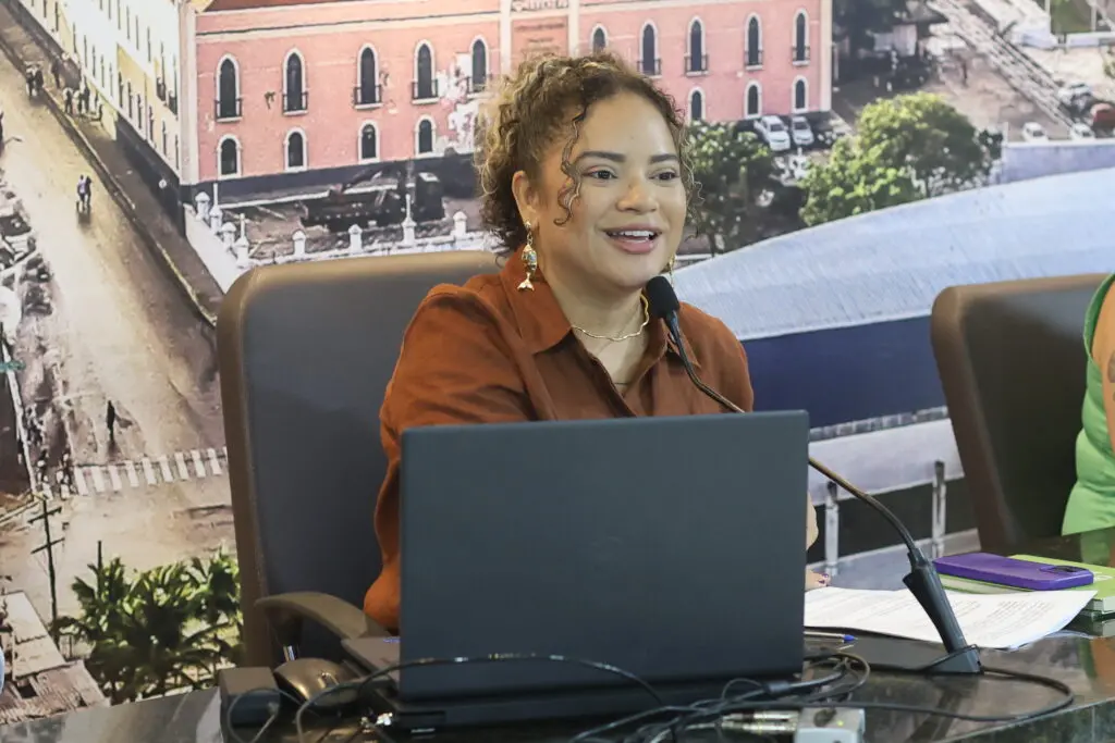 Participantes de uma audiência pública estão reunidos em torno de uma grande mesa em formato de 