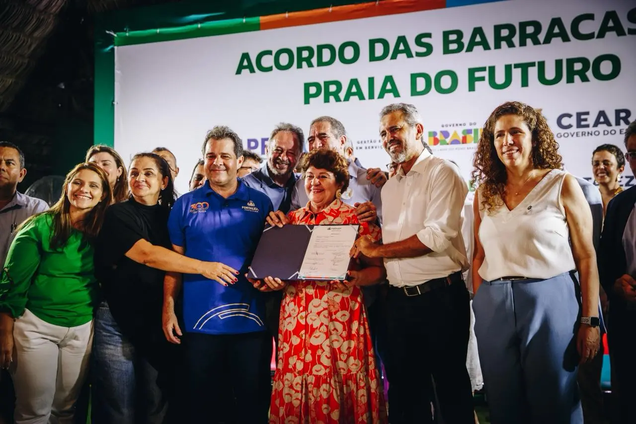 pessoas seguram placa indicando assinatura de acordo.