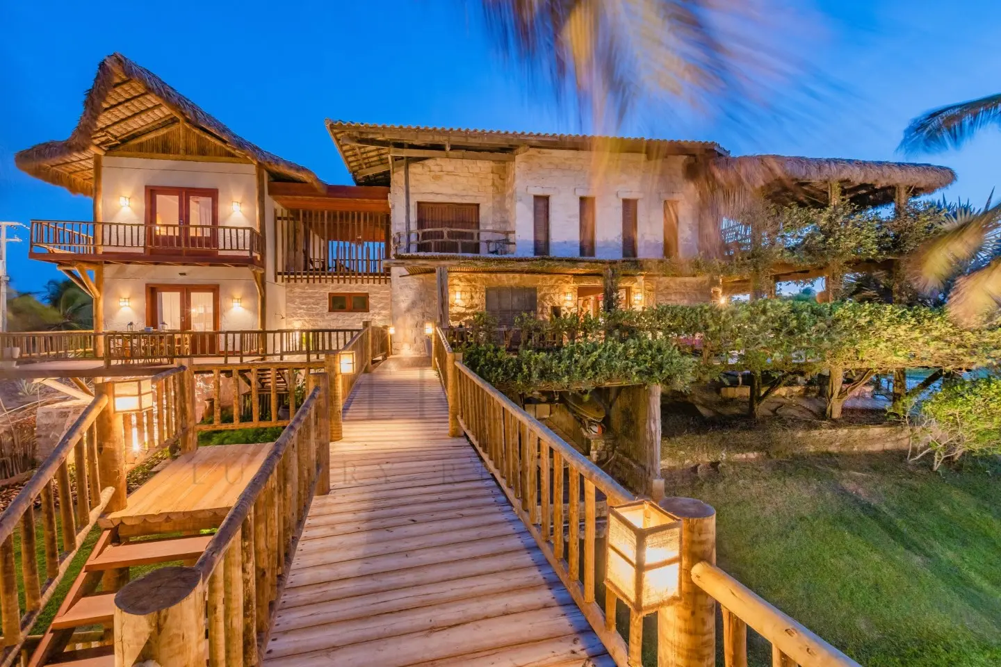 Fachada de uma casa ampla, de dois andares, com parede de pedra rústica e estruturas de madeira no exterior.