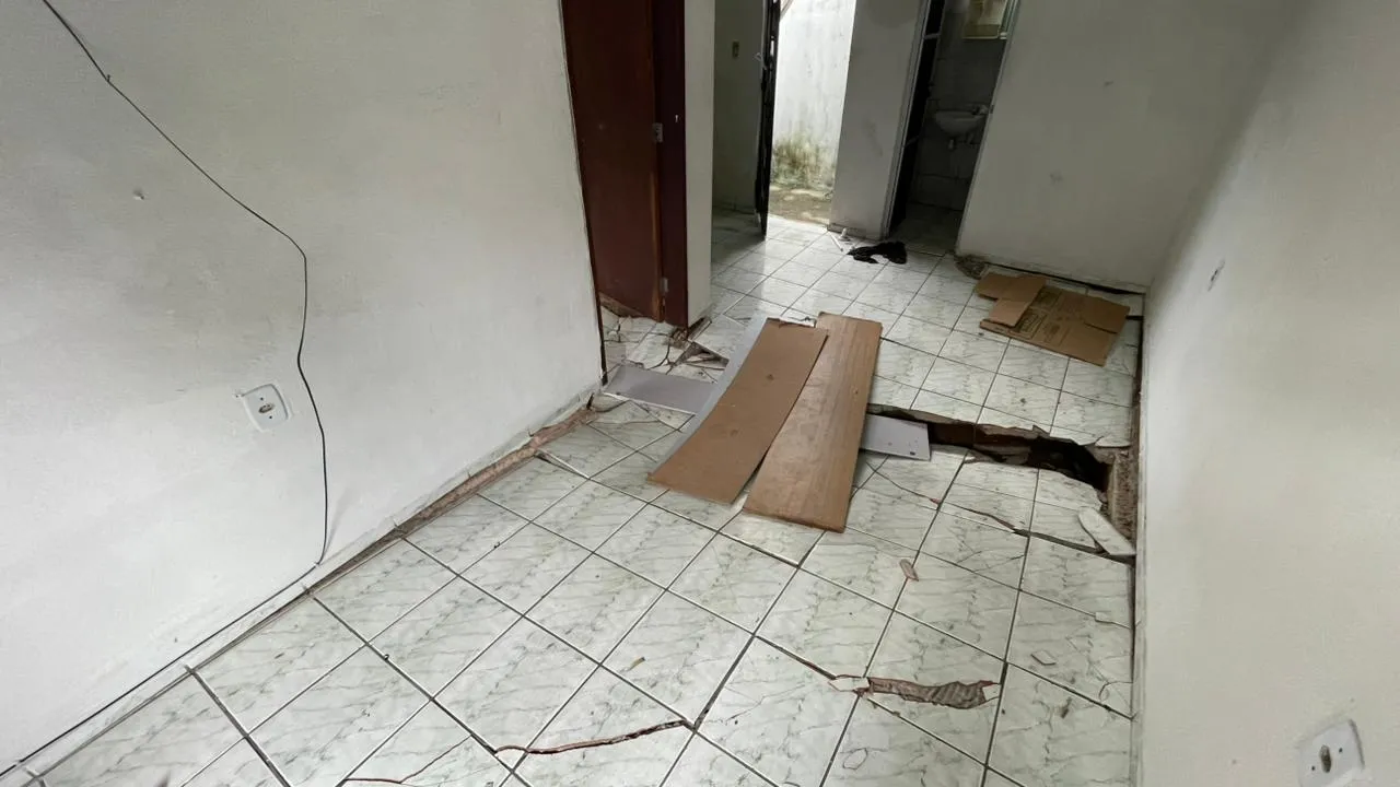Na parte interna de uma das casas da vila, é possível ver o chão cedendo e com rachaduras.